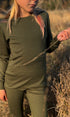 Child wearing a green merino wool long sleeve top and bottoms standing in a natural setting